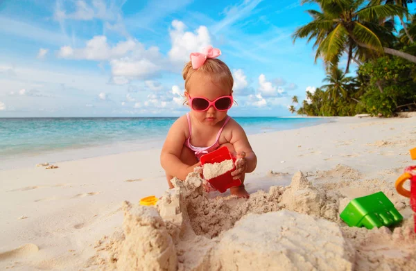 かわいい女の子は少し熱帯のビーチで砂と遊ぶ — ストック写真