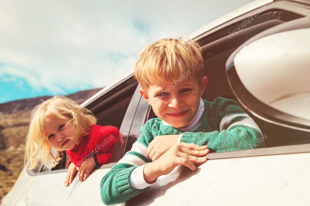 happy little boy and girl travel by car in mountains