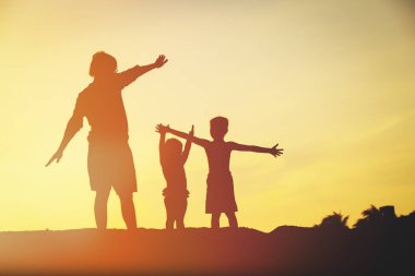 Baba ile oğlu ve kızı siluetleri oyun gün batımında