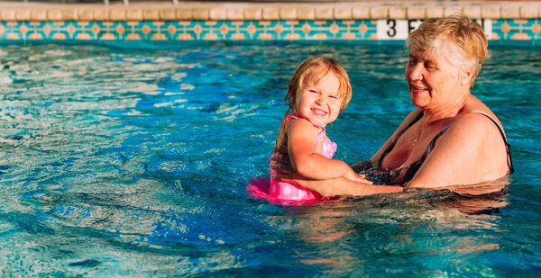 grandmother teaching little granddaughter to swim