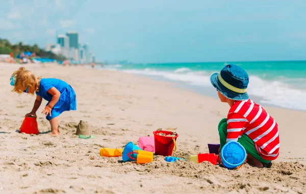 Malý chlapec a dívka hrají s pískem na pláži v létě — Stock fotografie