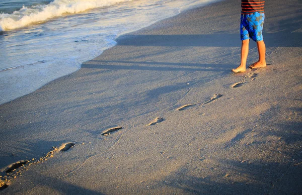 Menino andando na praia deixando pegada na areia — Fotografia de Stock