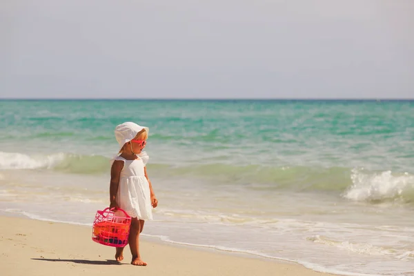 Bambina con giocattoli cammina sulla spiaggia di sabbia — Foto Stock