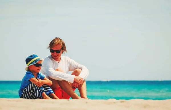 Père et petit fils parlant assis sur la plage — Photo