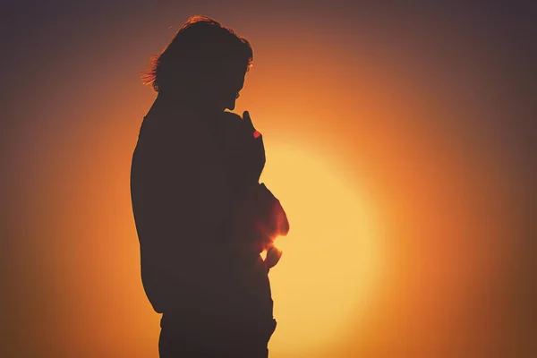Silhouettes of father and little newborn baby at sunset — стоковое фото