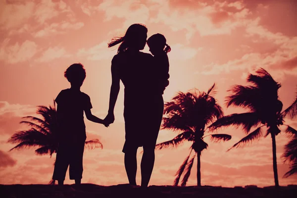 Matka a dvě děti procházky při západu slunce pláž — Stock fotografie