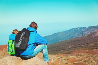 Baba ve oğul dağlarda yürüyüş yapıyor.