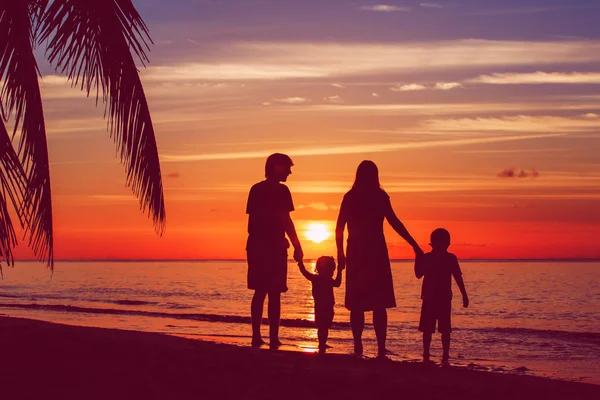 Familia feliz con dos niños en la playa del atardecer — Foto de Stock