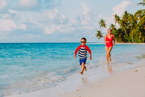 Мать и сын бегают в воде по пляжу — стоковое фото