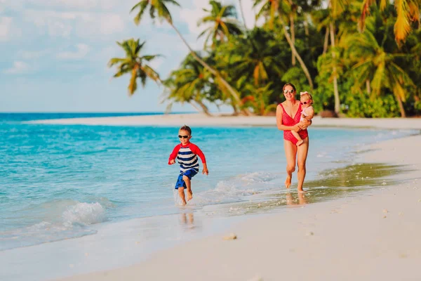 Anne ve kız kardeşi plajda çalışan mutlu küçük çocuk