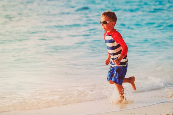 Bambino correre spruzzi d'acqua sulla spiaggia — Foto Stock