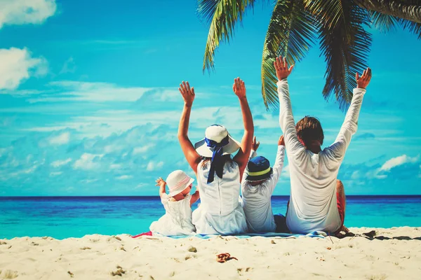 Lycklig familj med två barn händer upp på stranden — Stockfoto