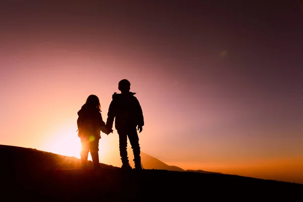 Silhouettes de petits garçons et filles en randonnée au coucher du soleil — Photo