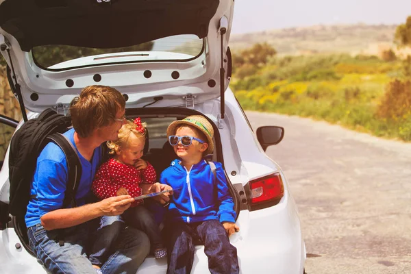 Samochód rodzinny podróży - ojciec z dwójką dzieci patrząc na mapę na drodze — Zdjęcie stockowe