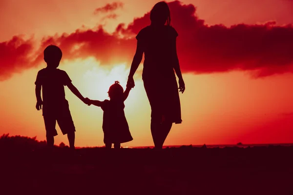 Madre e due bambini che camminano sulla spiaggia al tramonto — Foto Stock