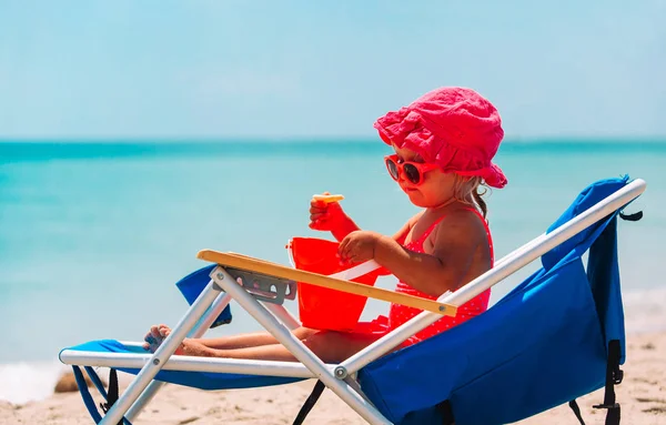 Malá holčička hrát na židli na tropické pláži — Stock fotografie