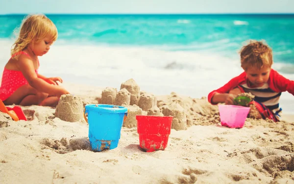 Kisfiú és a lány épület homokvár a strandon — Stock Fotó