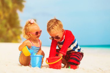 Çocuklar yaz plajında kumla oynarlar.