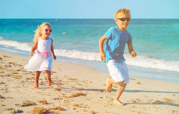 Pieni poika ja tyttö juoksee rannalla — kuvapankkivalokuva