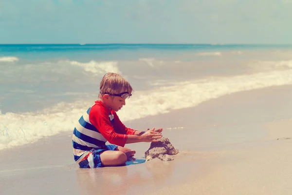 Маленький хлопчик грає в пісок на літньому пляжі — стокове фото