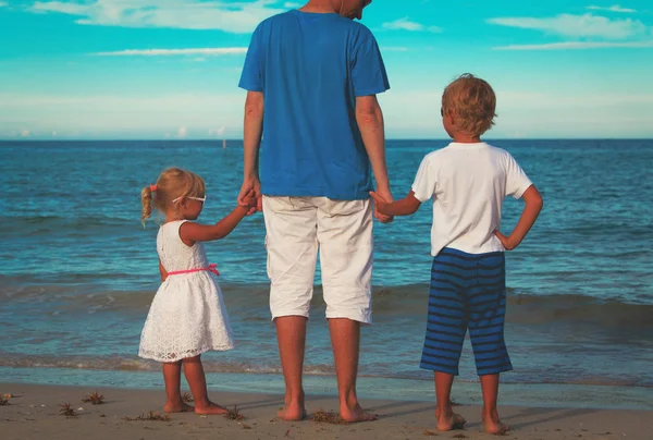 Vader en twee kinderen walking op strand — Stockfoto