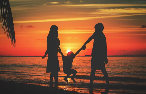 Família feliz com duas crianças jogar na praia do pôr do sol — Fotografia de Stock