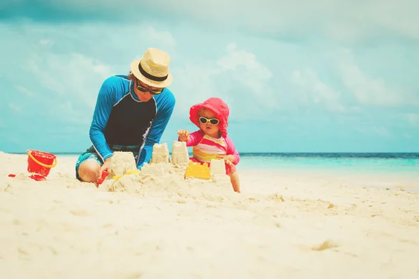 Otec a malá dcerka hrát s pískem na pláži — Stock fotografie