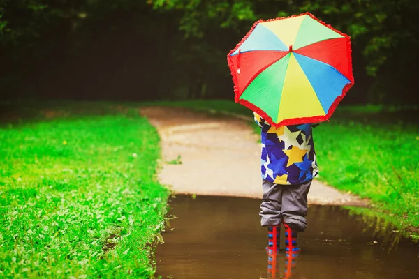 Niño pequeño con paraguas colorido jugar en el agua — Foto de Stock
