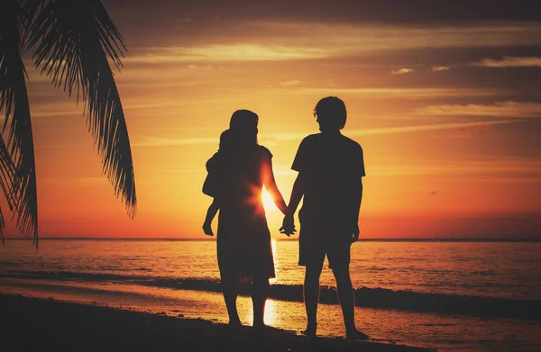 Família feliz com criança juntos ao pôr do sol — Fotografia de Stock