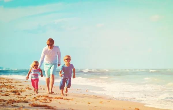 Père avec petit fils et fille courir à la plage — Photo
