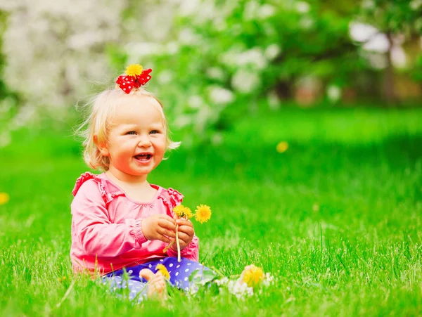 Schattig klein meisje met bloemen in de lente natuur — Stockfoto