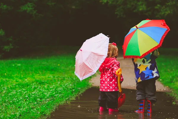 Little boy and girl with umbrellas playing in spring Stock Photo