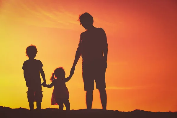 Pai com pequeno filho e filha andando ao pôr do sol — Fotografia de Stock