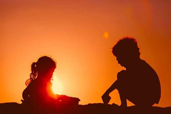 Little boy and girl play at sunset beach — Stock Photo, Image