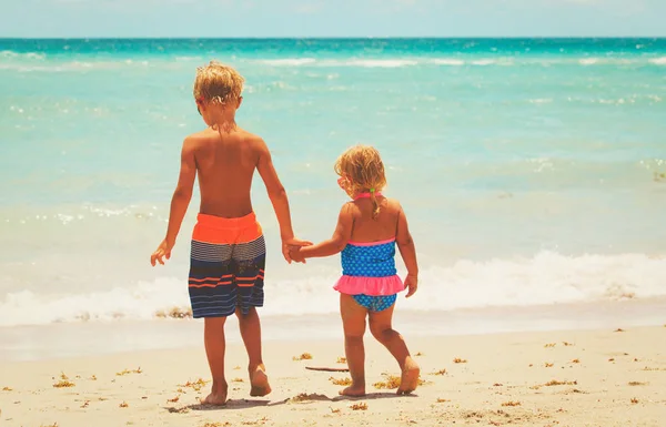 Petit garçon et fille aller nager sur la plage — Photo