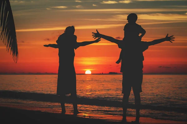 Família feliz com duas crianças jogar na praia do pôr do sol — Fotografia de Stock