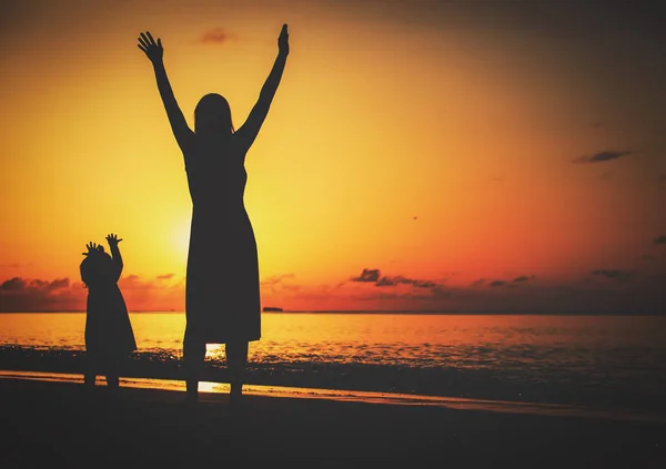 Silhouet van gelukkige moeder en kleine dochter bij zonsondergang — Stockfoto