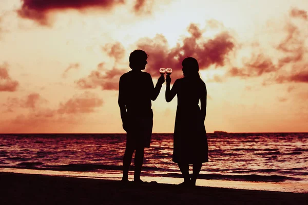 Silueta de pareja bebiendo vino en la playa al atardecer — Foto de Stock