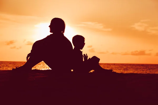 Pai e filho olhando para o pôr do sol na praia — Fotografia de Stock