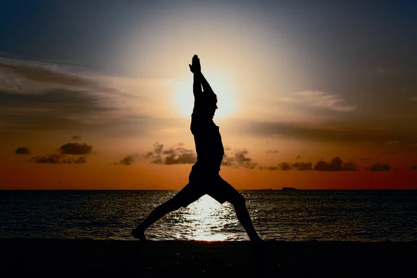 Silhouet van jonge man doen yoga bij zonsondergang — Stockfoto