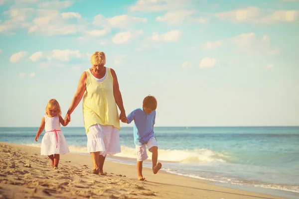 Бабушка с детьми маленький мальчик и девочка на пляже — стоковое фото