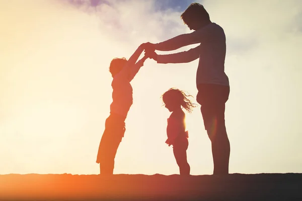 Padre e due bambini che giocano sul cielo del tramonto — Foto Stock