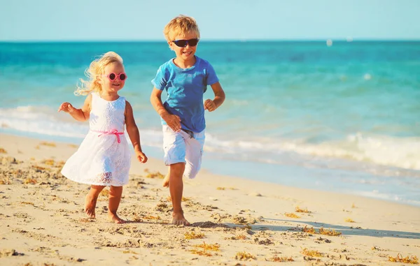 Kleine jongen en meisje draait op strand — Stockfoto