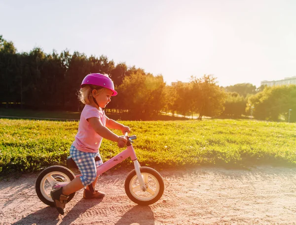 Bambina con casco in sella alla bici al tramonto — Foto Stock