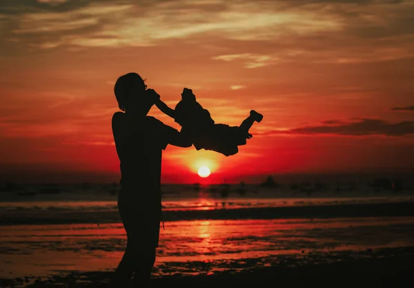 Padre e piccolo figlio silhouette giocare al tramonto — Foto Stock