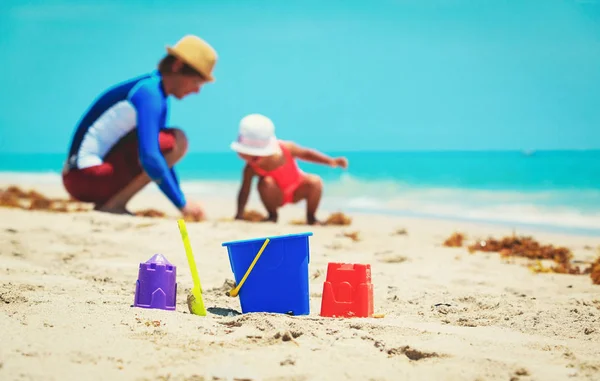 Dětské hračky a otec s malou dcerou hraje na pláži — Stock fotografie