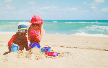Çocuklar yaz plajında kumla oynarlar.