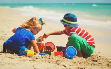 Çocuklar yaz plajında kumla oynarlar.