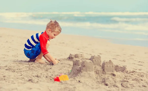 Malý chlapec hrát s pískem na letní pláži — Stock fotografie