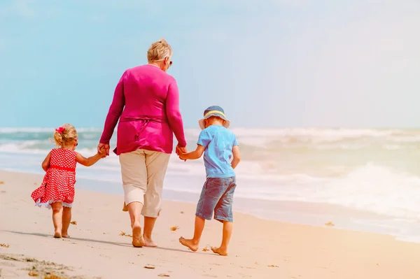 grandmother with kids- little boy and girl- walk at beach